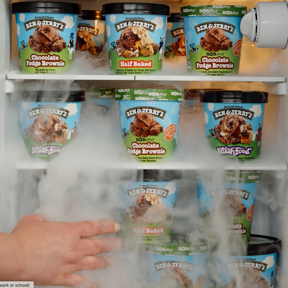hand in front of a freezer full of ice cream pints