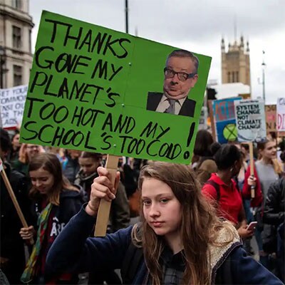 Girl holding sign reading ‘Thanks Gove*, My planet’s too hot and my school’s too cold’  at a rally